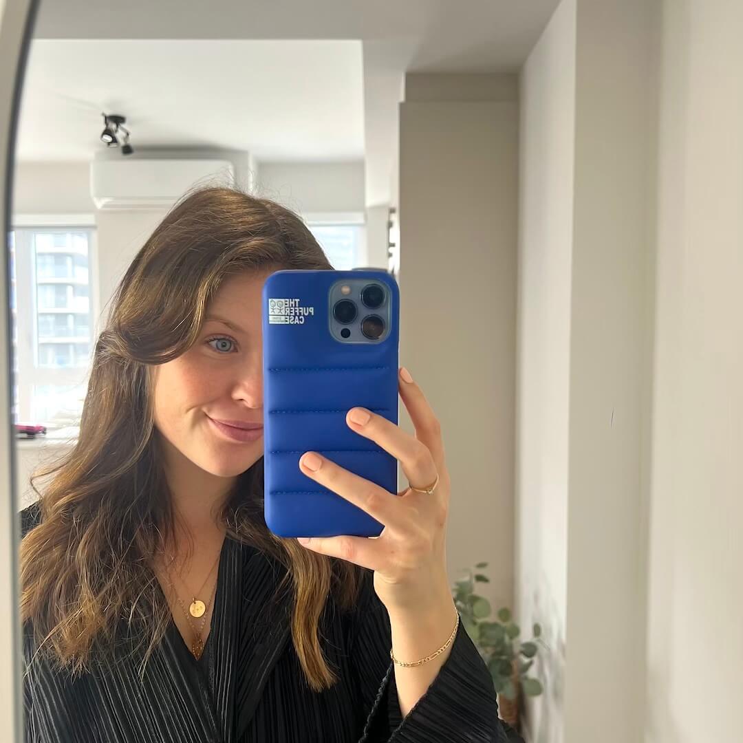 Person holding a blue phone case in front of a mirror