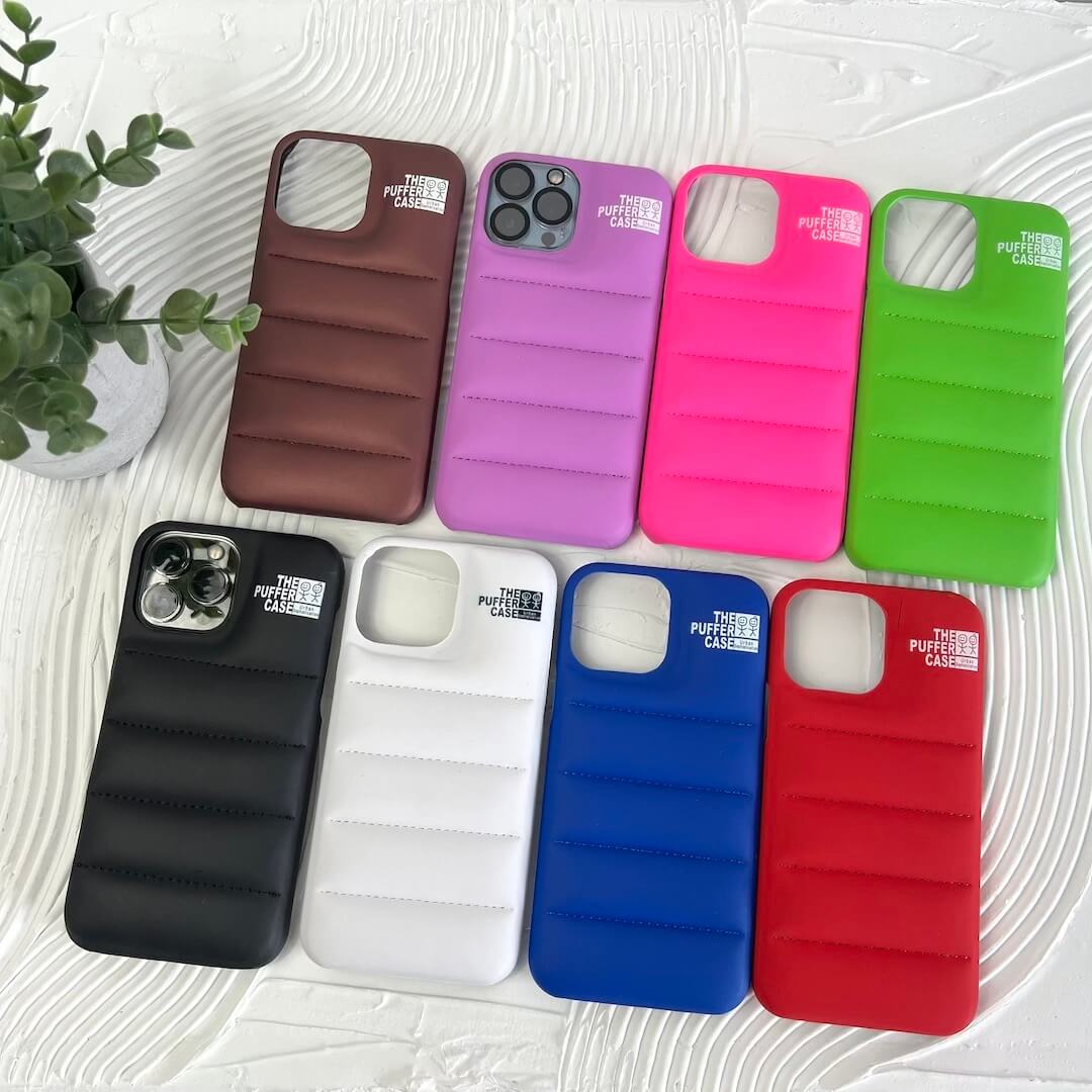 Assorted colorful phone cases on a textured surface with a plant in the corner.