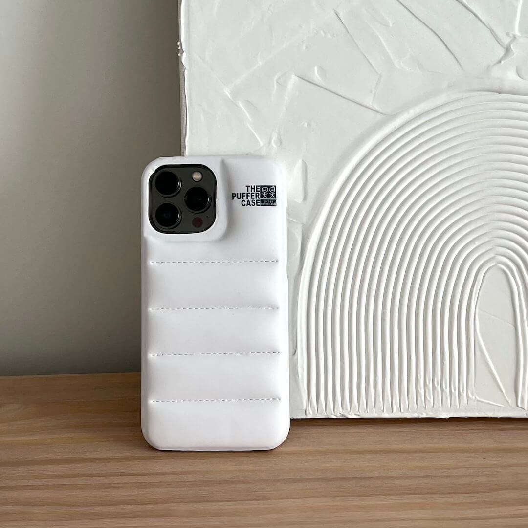 White phone case with brand name on a wooden surface and textured wall background
