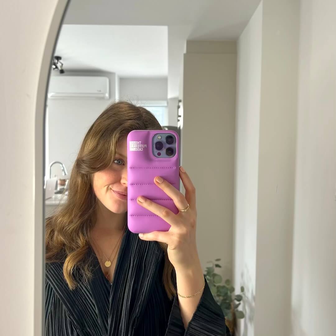Person holding a purple phone case in front of a mirror