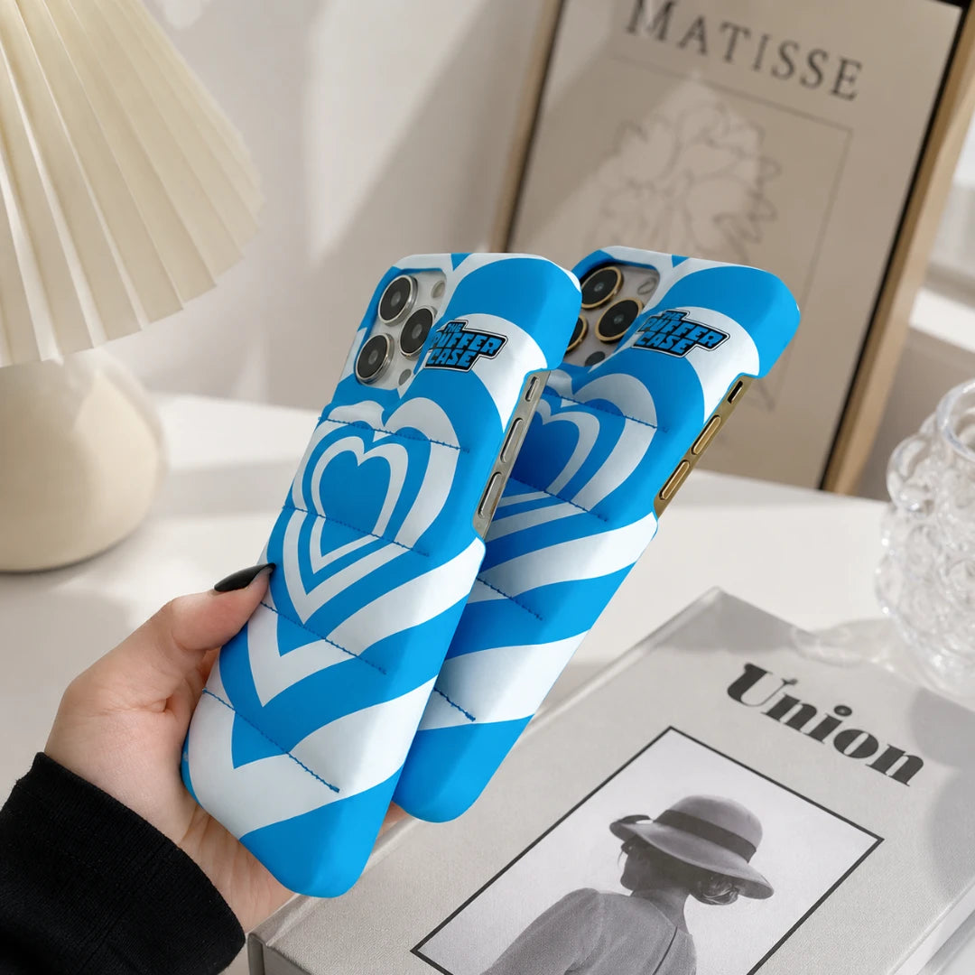 Josh & Tate - PuffHeart™ Quilted iPhone Case - Blue and white phone case with heart design held by a hand on a table.