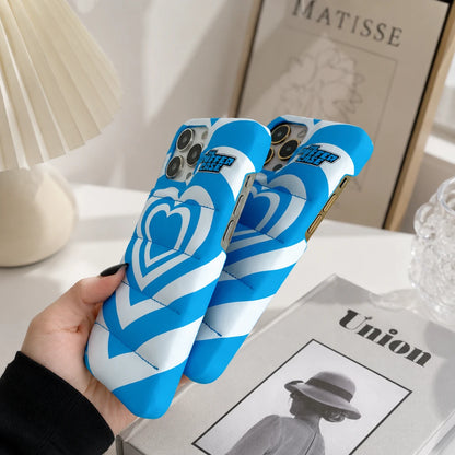 Josh & Tate - PuffHeart™ Quilted iPhone Case - Blue and white phone case with heart design held by a hand on a table.