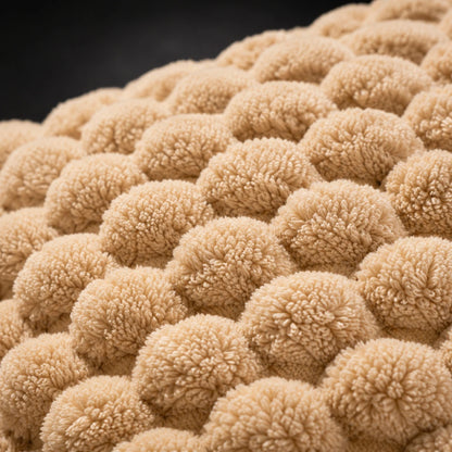 Josh & Tate - PuffKnot™ Bobble Cushion Cover - Close-up of a textured beige fabric with a repeating tufted or pom-pom-like pattern against a dark background.