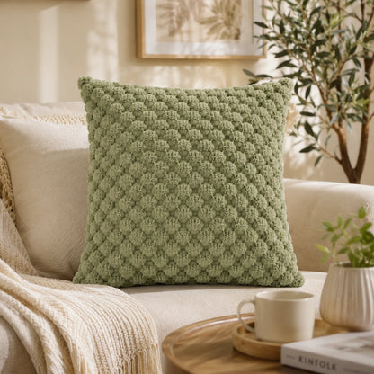 Josh & Tate - PuffKnot™ Bobble Cushion Cover - A square sage green textured throw pillow with a raised diamond pattern, styled on a cream sofa in a warm, sunlit living room setting.