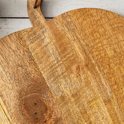 Josh & Tate - Pumpkin Wooden Cutting Board - Close-up of a wooden cutting board with a handle on a light wooden floor.