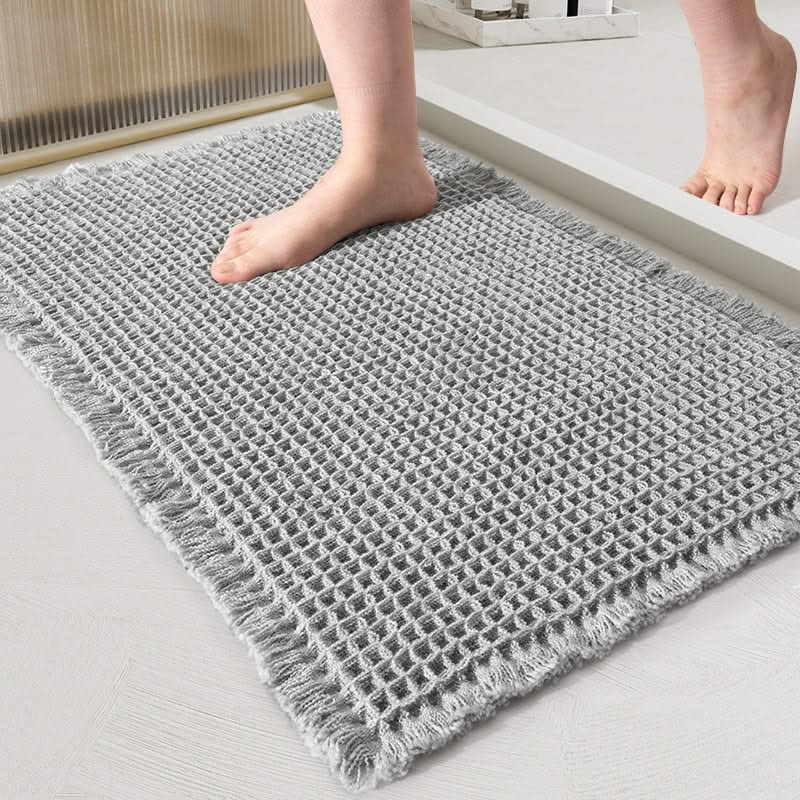 Gray textured rug on a light wooden floor with a person's feet stepping onto it.