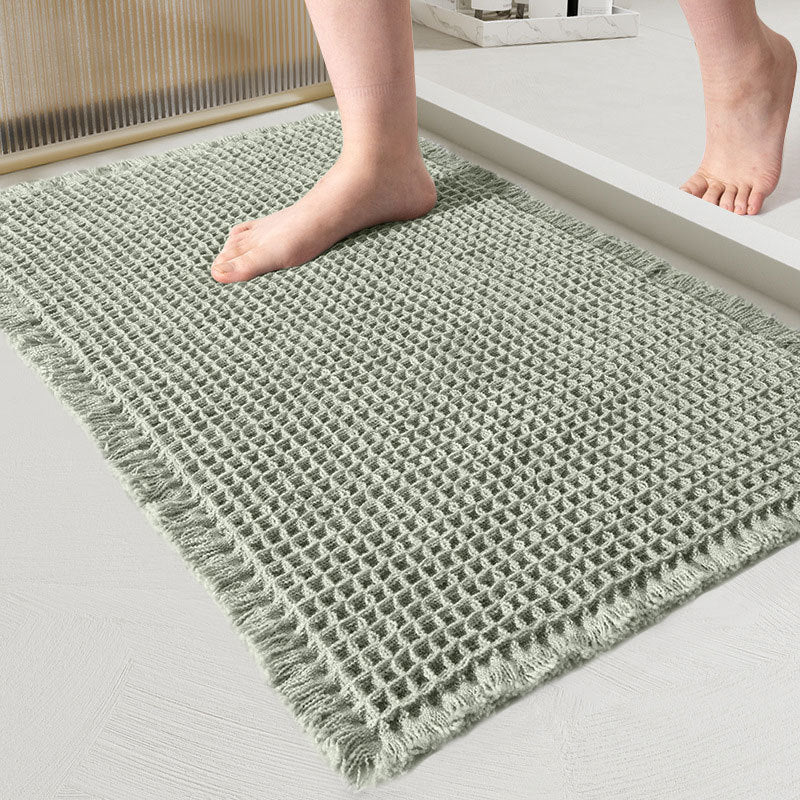 Green textured rug on a light gray floor with a person's feet stepping onto it.