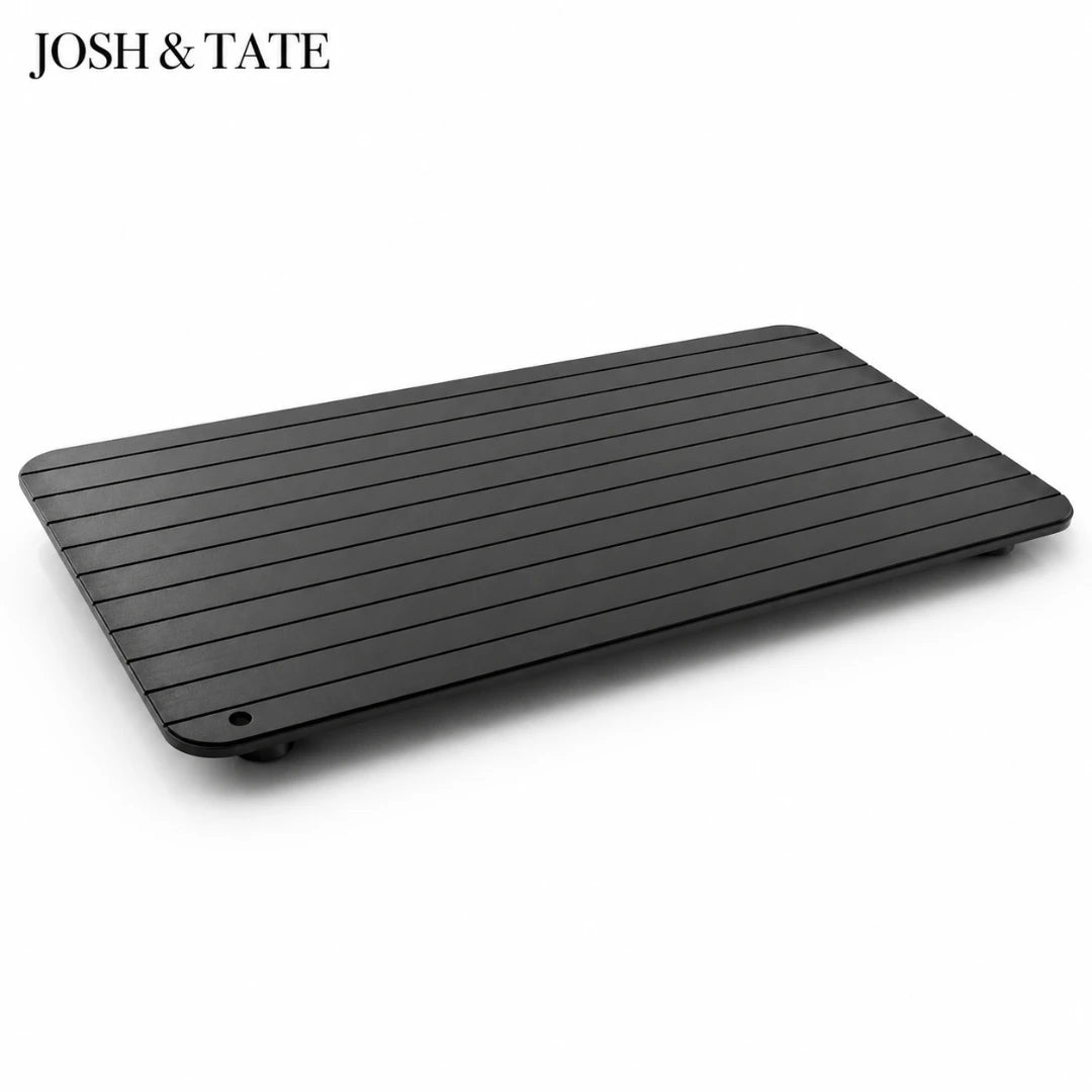 Josh & Tate - QuickThaw No-Power Defrost Tray - Black rectangular object with horizontal slats on a white background, featuring the brand 'JOSH & TATE'.