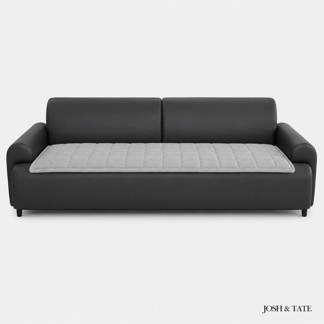 Josh & Tate - QuiltDrape™ Corduroy Sofa Cover - Black sofa with a gray quilted cushion on a white background, branded 'Josh & Tate'.