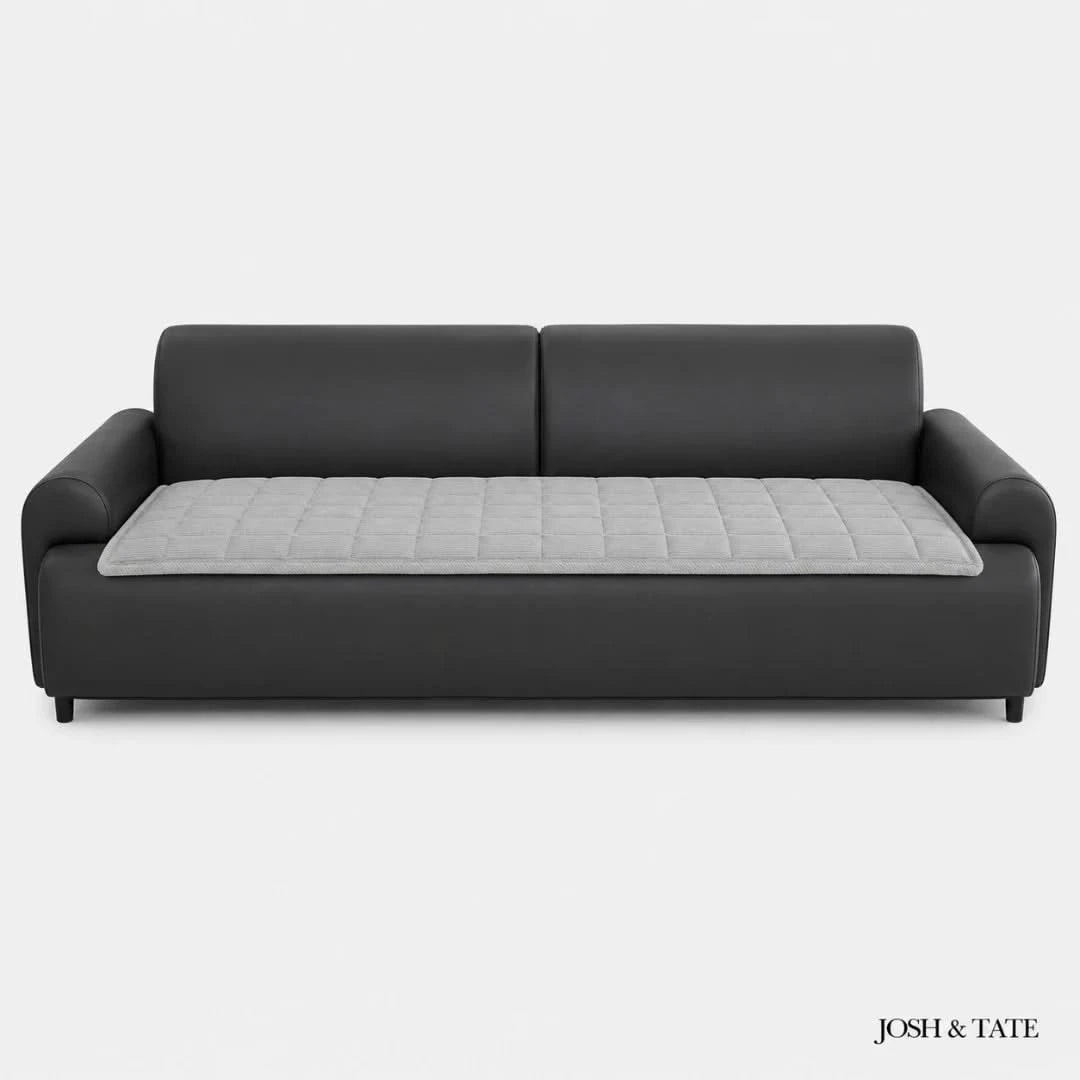 Josh & Tate - QuiltDrape™ Corduroy Sofa Cover - Black sofa with a gray quilted cushion on a white background, branded 'Josh & Tate'.