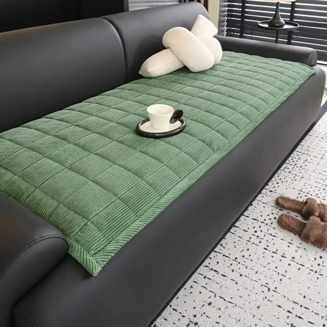 Josh & Tate - QuiltDrape™ Corduroy Sofa Cover - Green quilted sofa cover on a gray sofa with a cup and saucer on a small table.