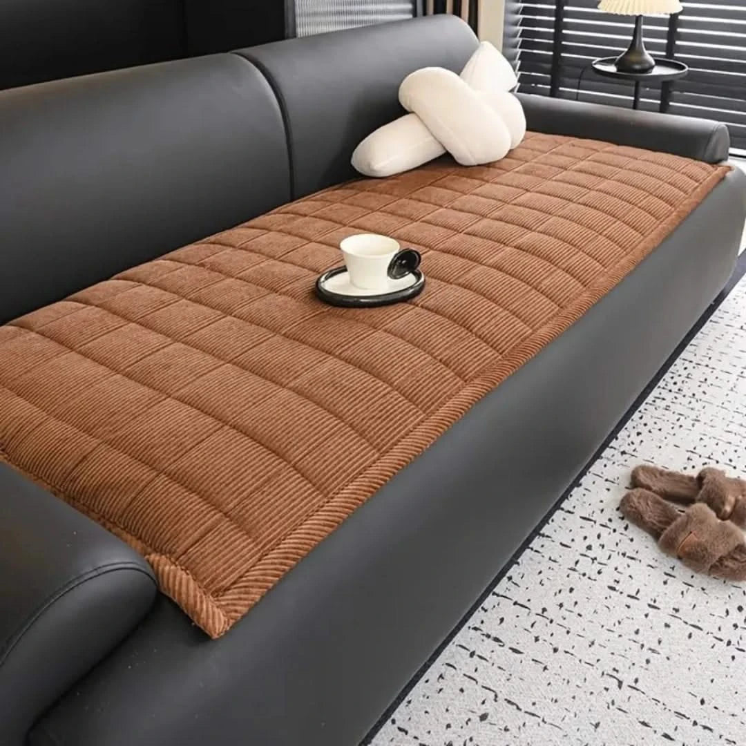 Josh & Tate - QuiltDrape™ Corduroy Sofa Cover - Brown quilted sofa cover on a gray sofa with a cup and saucer on a black coaster.