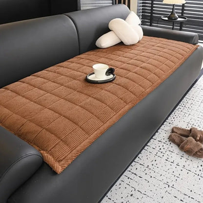 Josh & Tate - QuiltDrape™ Corduroy Sofa Cover - Brown quilted sofa cover on a gray sofa with a cup and saucer on a black coaster.