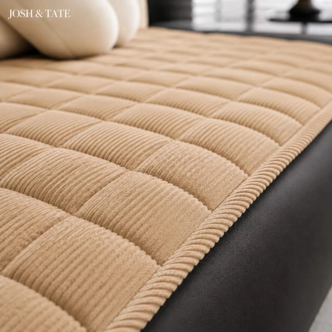 Josh & Tate - QuiltDrape™ Corduroy Sofa Cover - Beige quilted sofa cover on a black sofa with 'JOSH & TATE' branding.