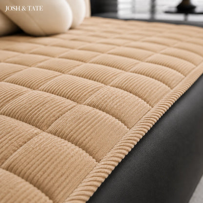 Josh & Tate - QuiltDrape™ Corduroy Sofa Cover - Beige quilted sofa cover on a black sofa with 'JOSH & TATE' branding.