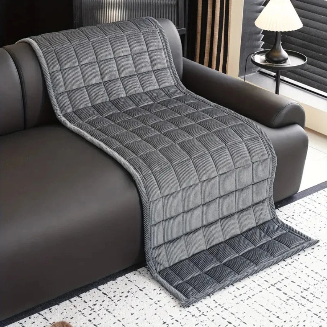 Josh & Tate - QuiltDrape™ Corduroy Sofa Cover - Gray quilted throw blanket draped over a brown sofa in a living room.