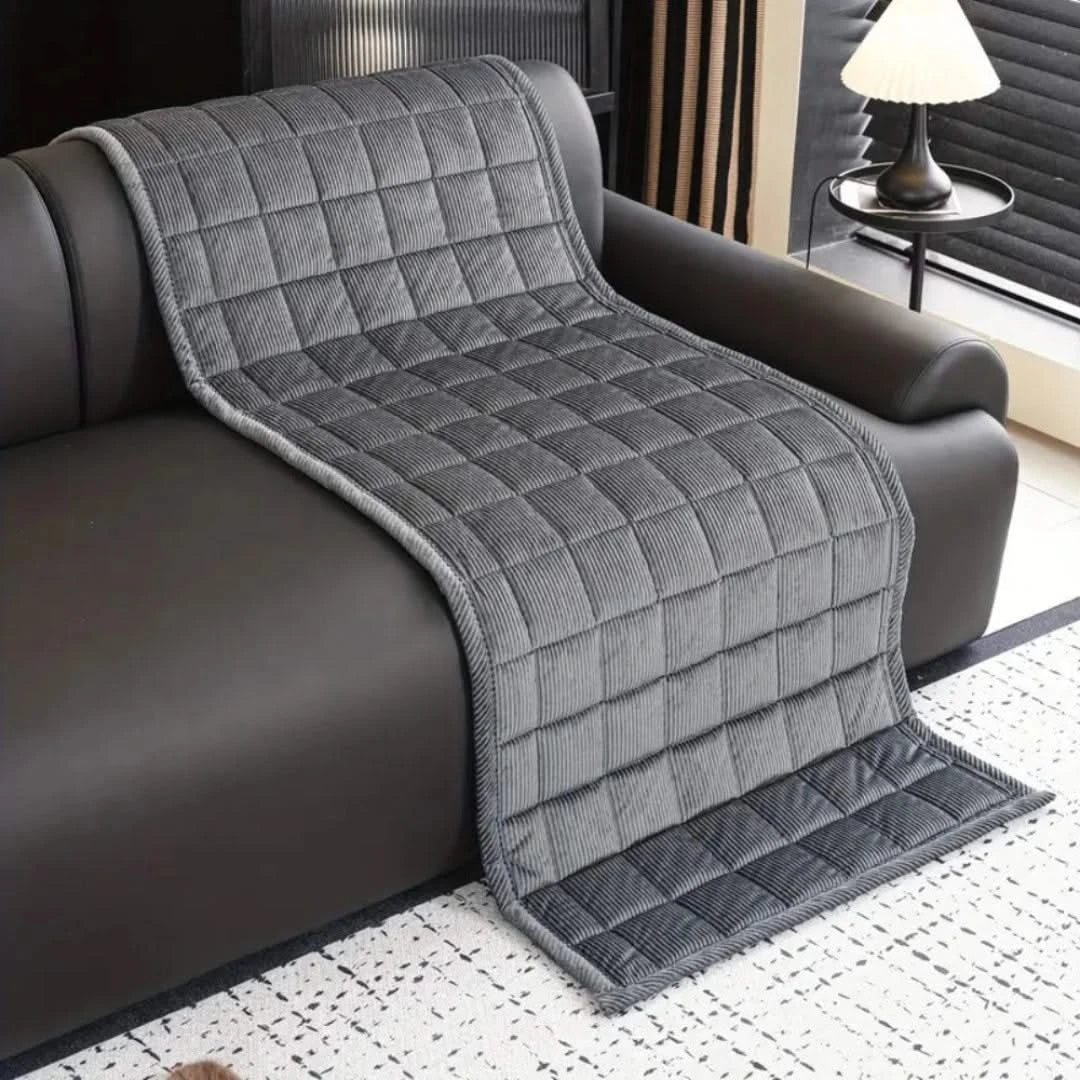 Josh & Tate - QuiltDrape™ Corduroy Sofa Cover - Gray quilted throw blanket draped over a brown sofa in a living room.