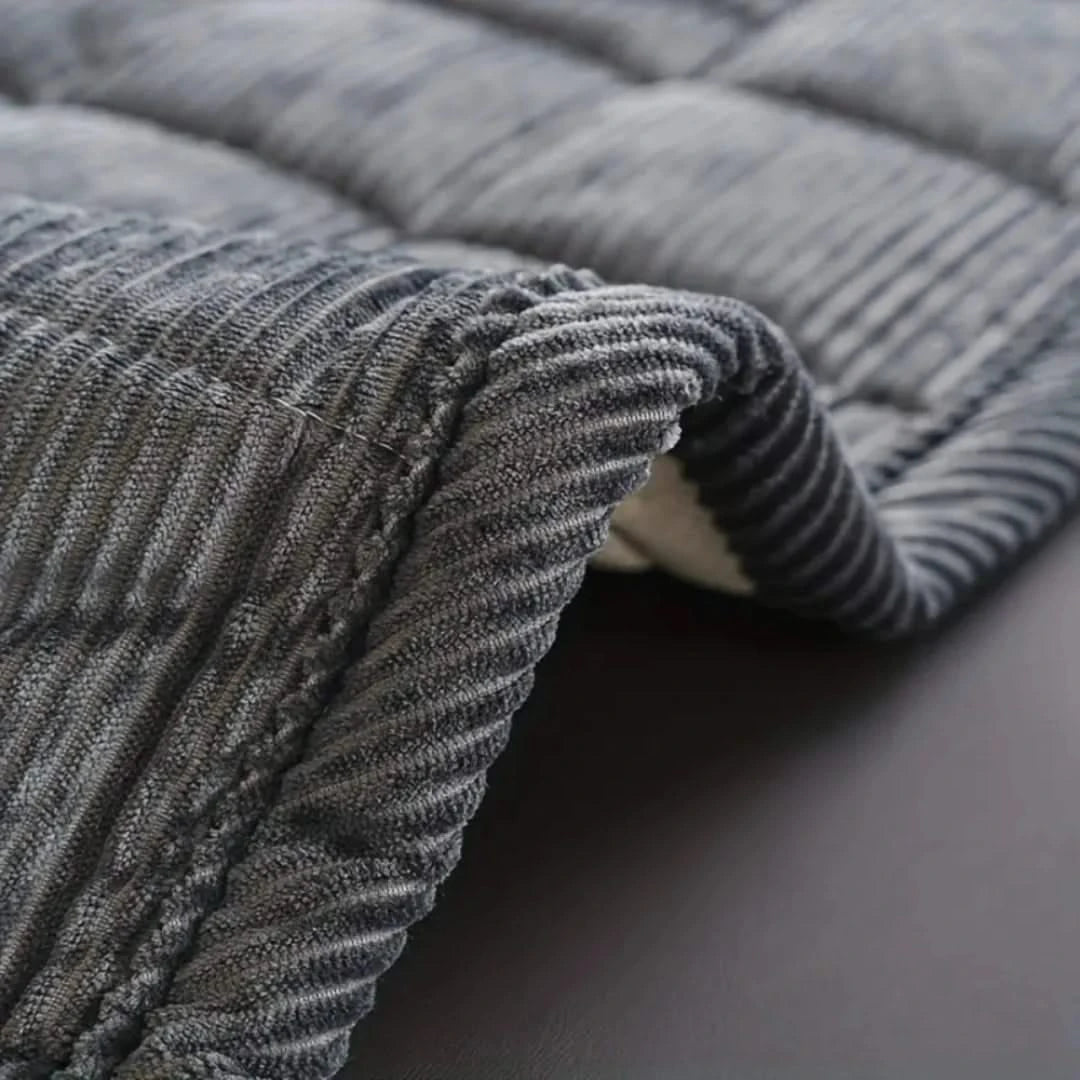 Josh & Tate - QuiltDrape™ Corduroy Sofa Cover - Close-up of a textured gray blanket on a dark surface