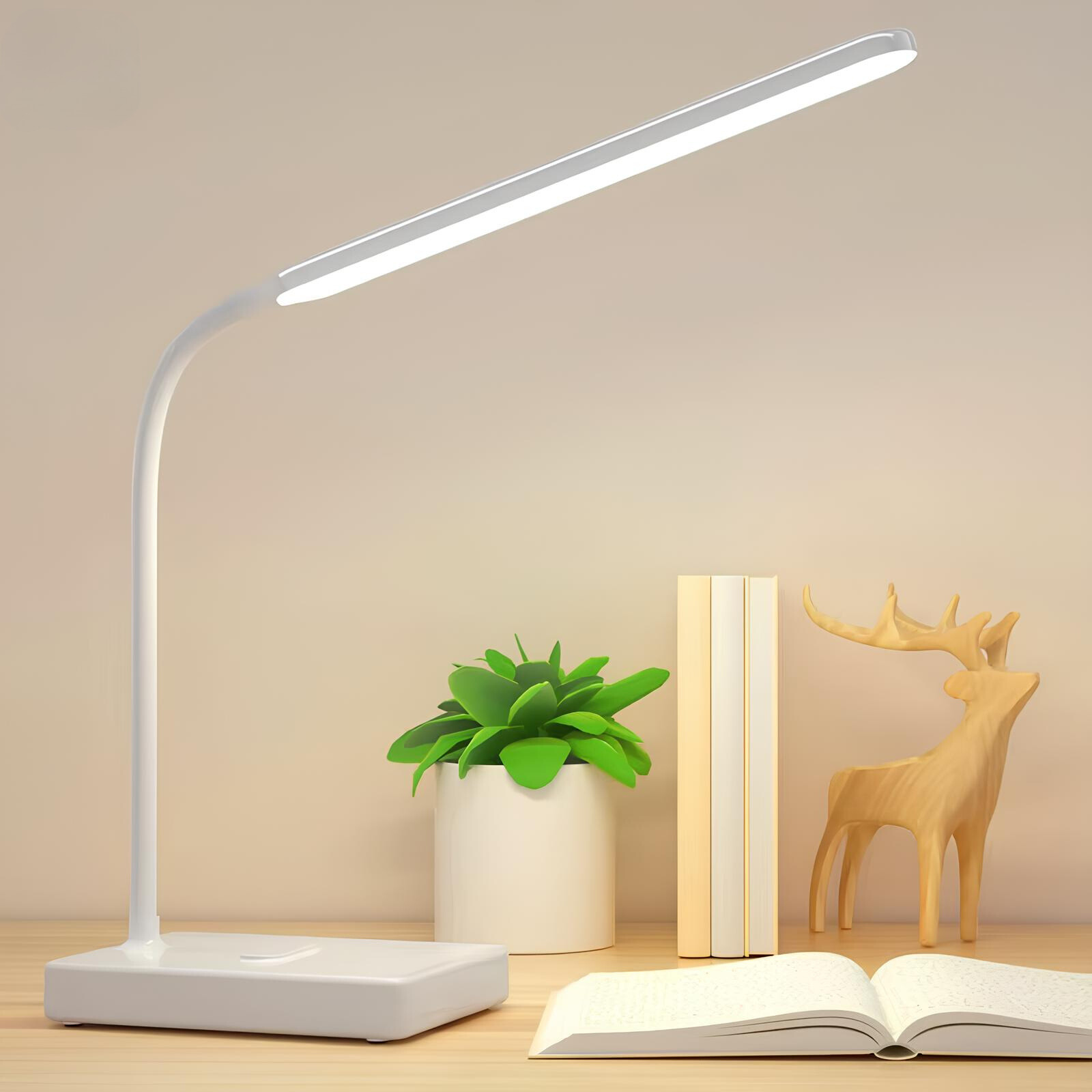 White LED desk lamp on a wooden surface with a plant, book, and wooden deer ornament.