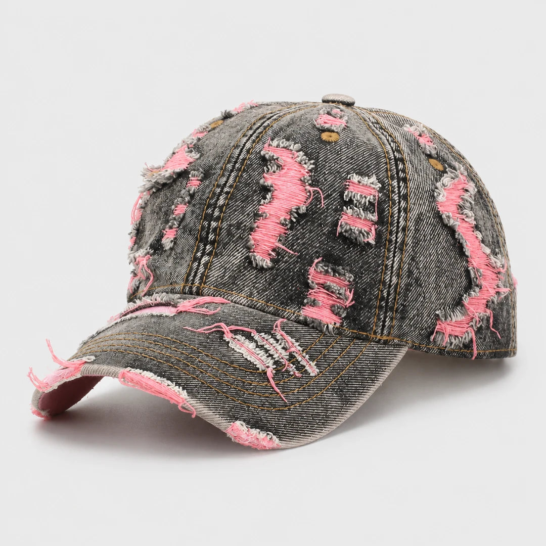 Josh & Tate - RaggedRow™ Distressed Denim Cap - A distressed baseball cap made of faded dark gray denim with bright pink frayed accents and ripped details, shown on a light gray background.