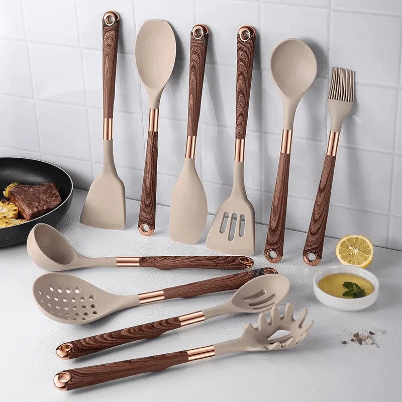 Set of kitchen utensils with wooden and rose gold handles on a kitchen counter.
