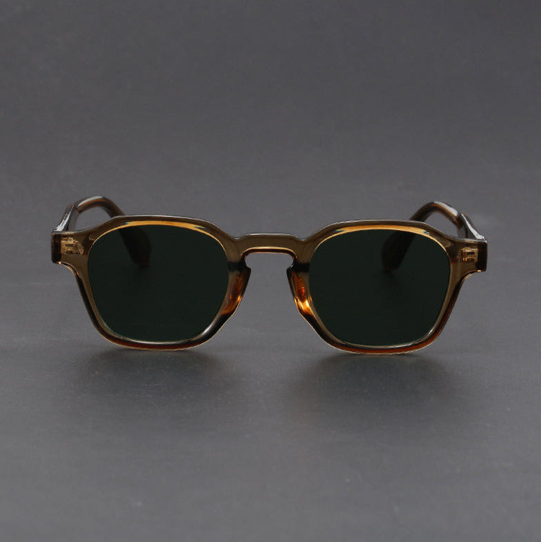 Sunglasses with a gold frame and dark lenses on a gray background