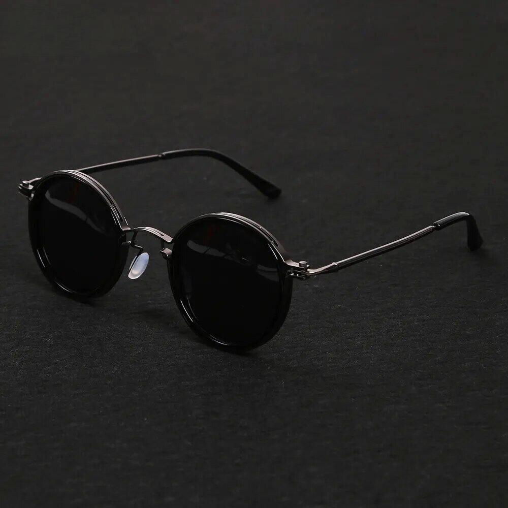 Round sunglasses with black lenses and thin metal frame on a dark background