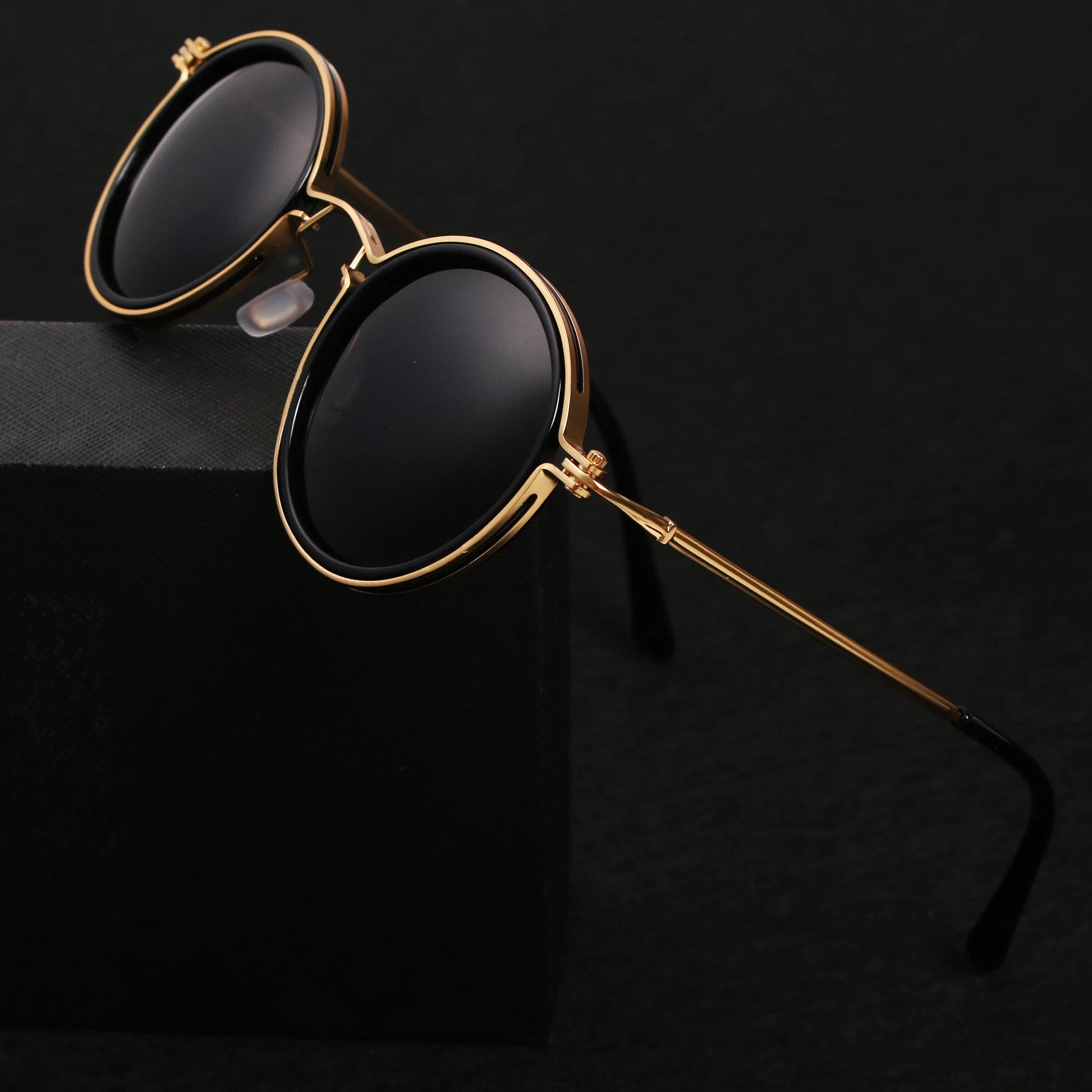 Gold-framed sunglasses with black lenses on a black background