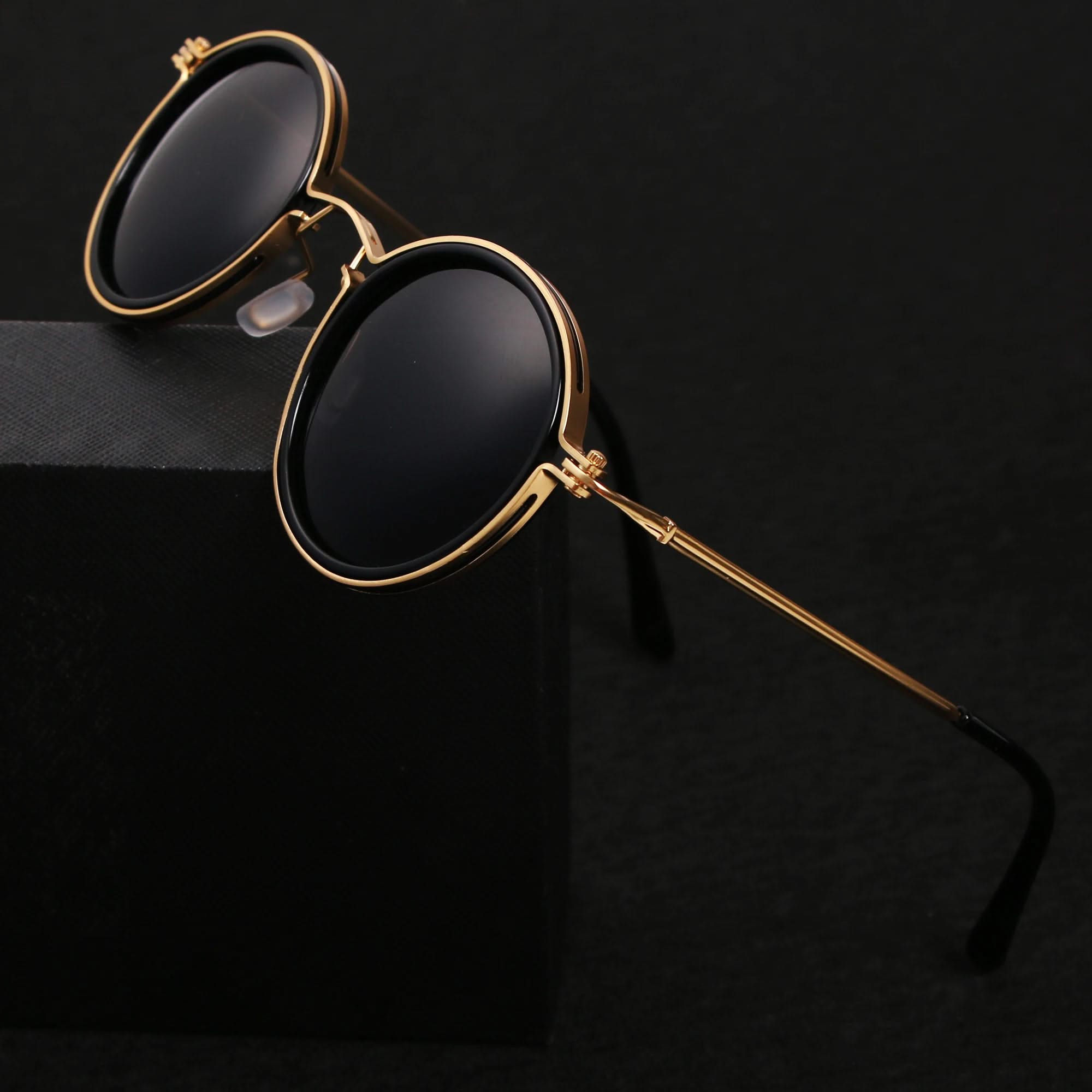 Gold-framed sunglasses with black lenses on a black background