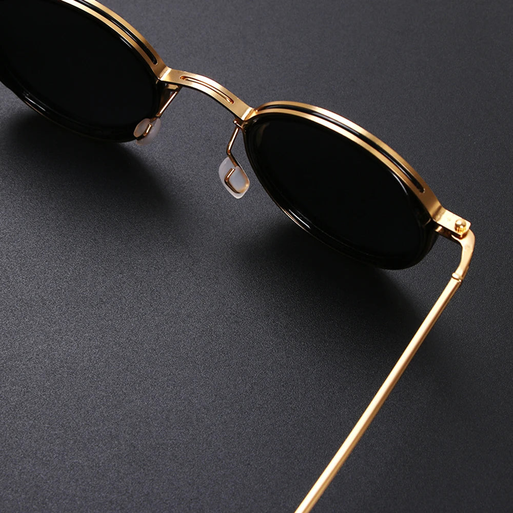 Gold-framed sunglasses with black lenses on a dark gray background