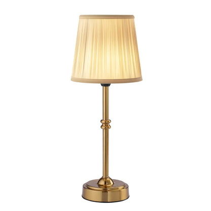 Table lamp with gold base and beige pleated shade on a white background