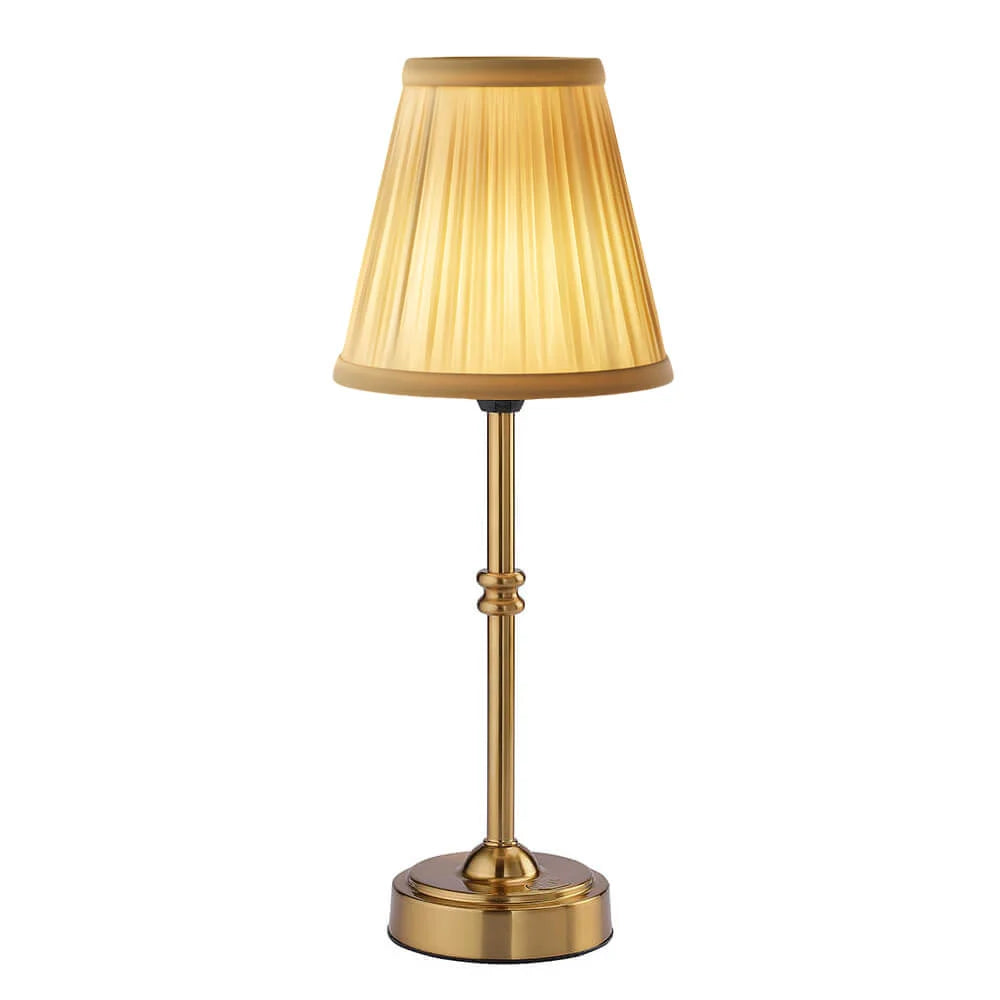 Gold table lamp with pleated shade on a white background
