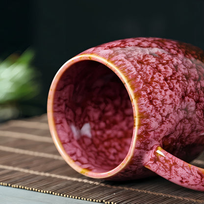 Red ceramic mug with textured surface on a woven mat