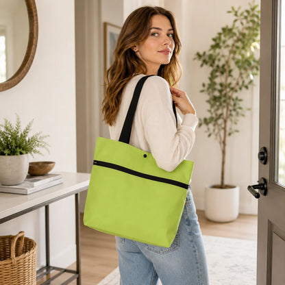 Josh & Tate - ReusableCart™ Foldable Shopping Bag - A woman in a home interior wearing a white long-sleeve top and light blue jeans, carrying a bright lime green tote bag with black straps and a black horizontal trim.