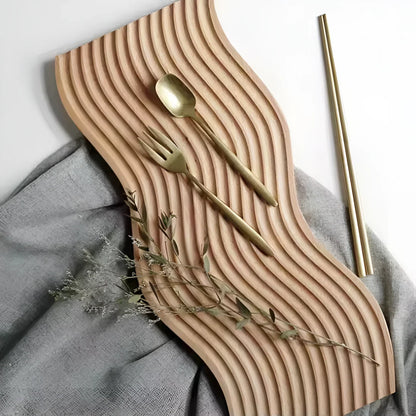 Josh & Tate - Ripple Wave Wooden Serving Tray - Wooden wavy placemat with gold cutlery on a gray fabric background