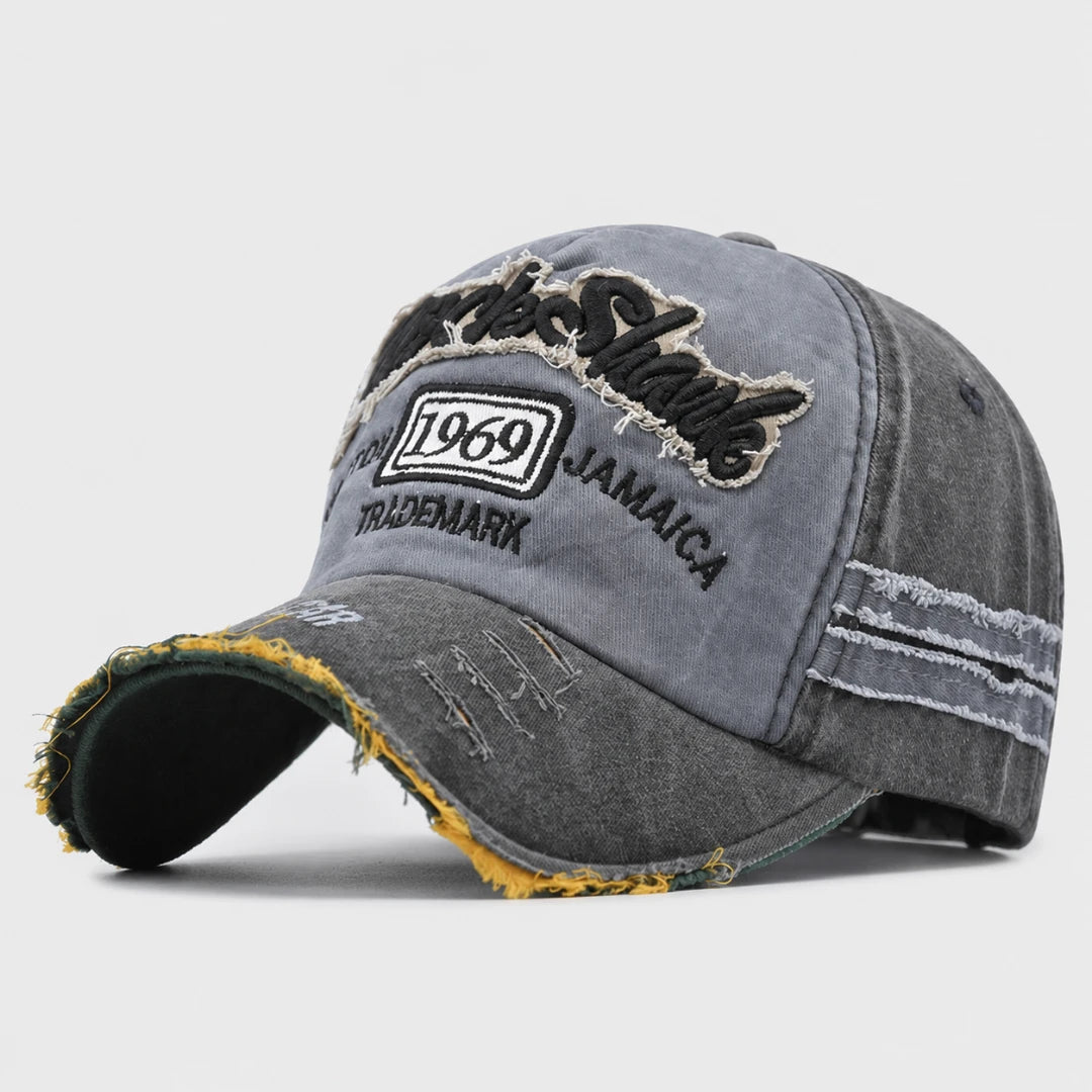 Josh & Tate - RockShank™ 1969 Baseball Cap - A distressed gray washed baseball cap with black embroidered text reading 'Sharks' and '1969 JAMAICA' on the front, plus frayed detailing along the brim and side panels, shown on a light gray background.