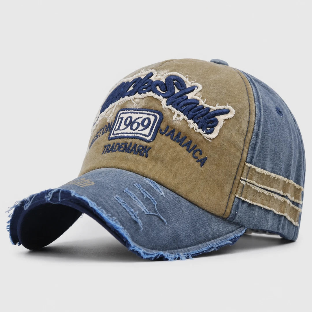 Josh & Tate - RockShank™ 1969 Baseball Cap - A distressed baseball cap featuring a tan front panel with 'Sharks' embroidered in blue, a '1969' patch, and 'JAMAICA' text, combined with blue denim panels on the sides and brim.
