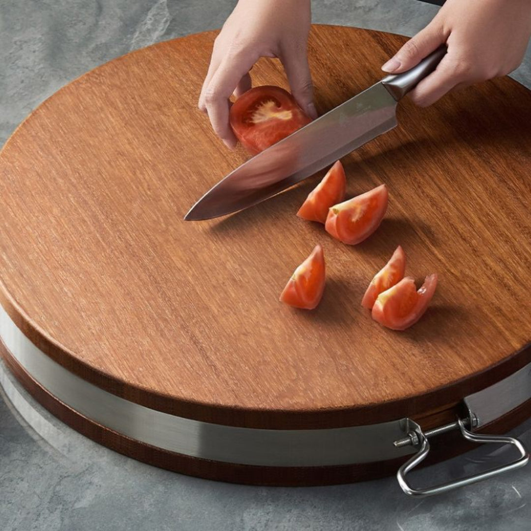 Person cutting a tomato on a wooden cutting board with a knife.