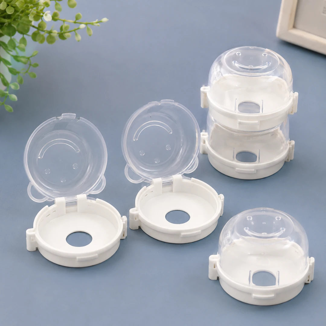 Josh & Tate - SafeKnob™ Child Safety Stove Covers - Four small clear plastic dome-shaped storage containers with white bases, arranged on a blue surface with a small plant in the corner.