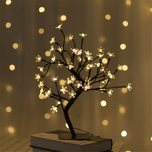Decorative LED tree with glowing lights on a book against a blurred light background