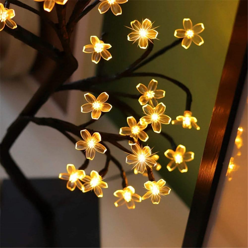 Flower-shaped string lights on a branch with a blurred background