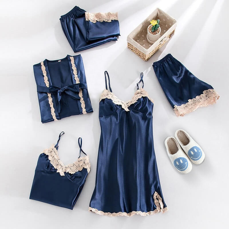 Navy blue satin pajama set with lace details on a white surface.