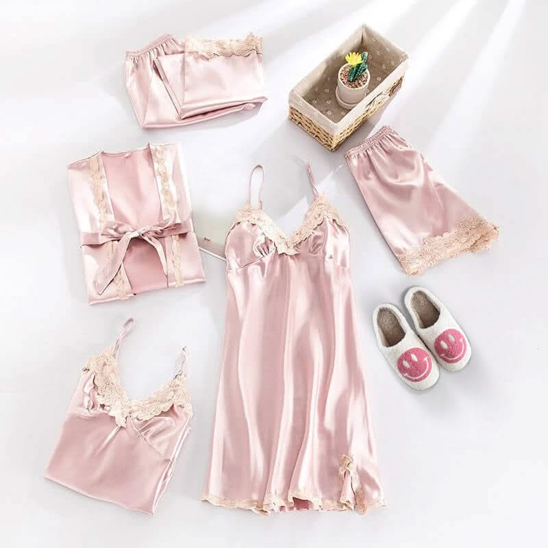 Pink satin pajama set with matching robe, slippers, and shorts on a white background