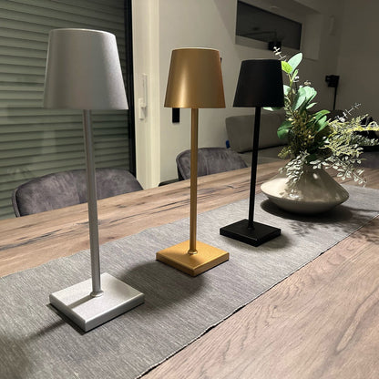 Three table lamps on a wooden table with a plant in the background