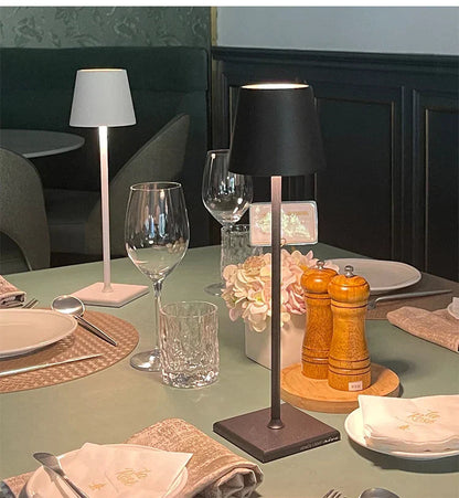 Table setting with a black table lamp, glasses, and cutlery in a restaurant.