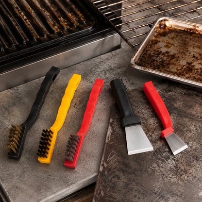 Josh & Tate - ScrubEdge™ 5-Piece Cleaning Set - Four barbecue cleaning tools arranged on a stone surface beside a grill: two wire brushes in black and yellow with dark bristles, and two scraper tools in black and red with silver metal blades. A dirty baking pan and grill grate are visible in the background.