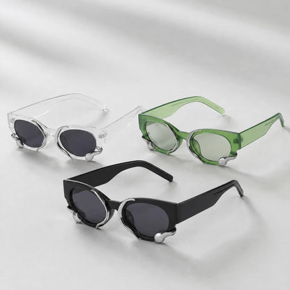 Josh & Tate - SerpentEdge™ Statement Sunglasses - Three pairs of sunglasses with unique angular metal frames are arranged on a light gray background. The sunglasses include clear frames with dark lenses, green translucent frames with light lenses, and black frames with dark lenses, each featuring silver decorative metal accents at the hinge.