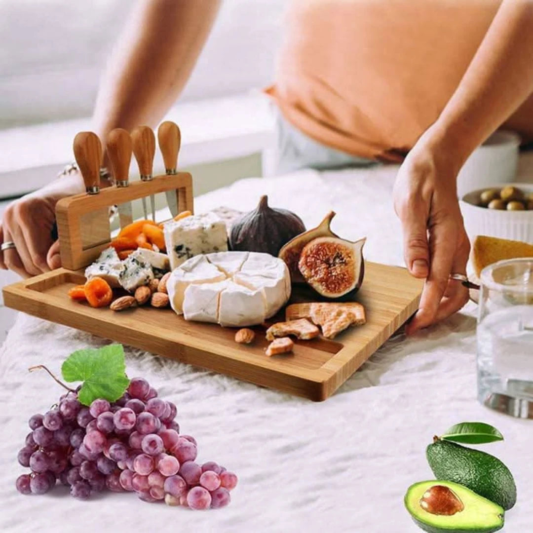 Josh & Tate - Serving Board Set with Built-In Knife Holder - Wooden charcuterie board with assorted cheeses, fruits, and nuts on a bed.