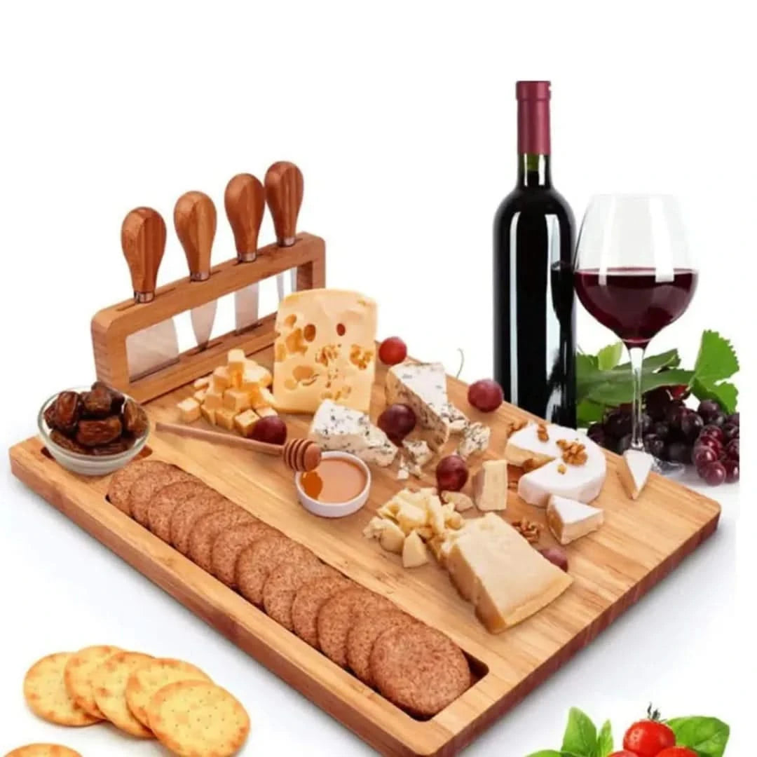 Josh & Tate - Serving Board Set with Built-In Knife Holder - Wooden cheeseboard with assorted cheeses, crackers, fruits, and a bottle of wine on a white background
