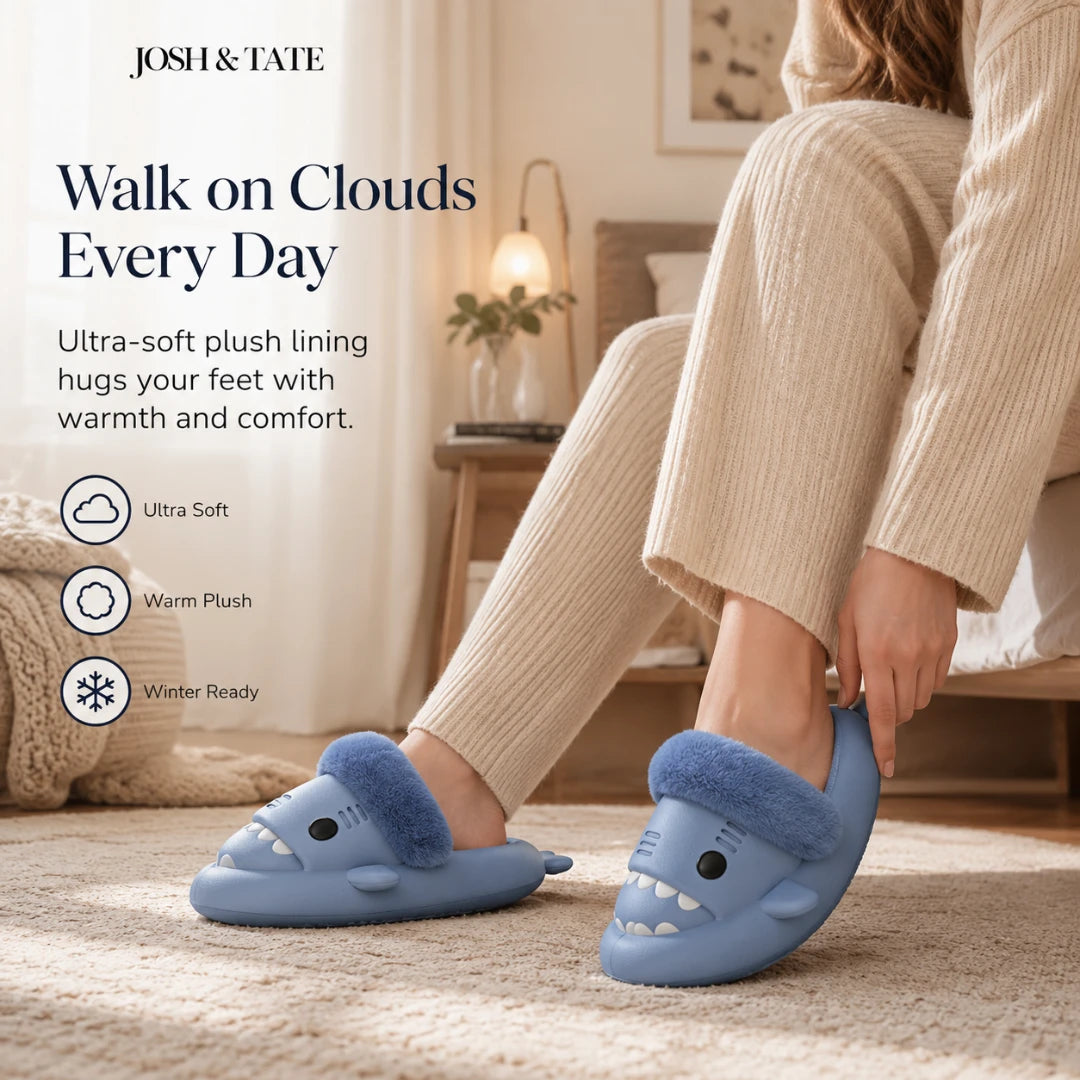 Josh & Tate - SharkStep™ Plush Slip-On Slipper - Person wearing blue slippers with a cartoon shark design, sitting on a couch in a cozy living room.